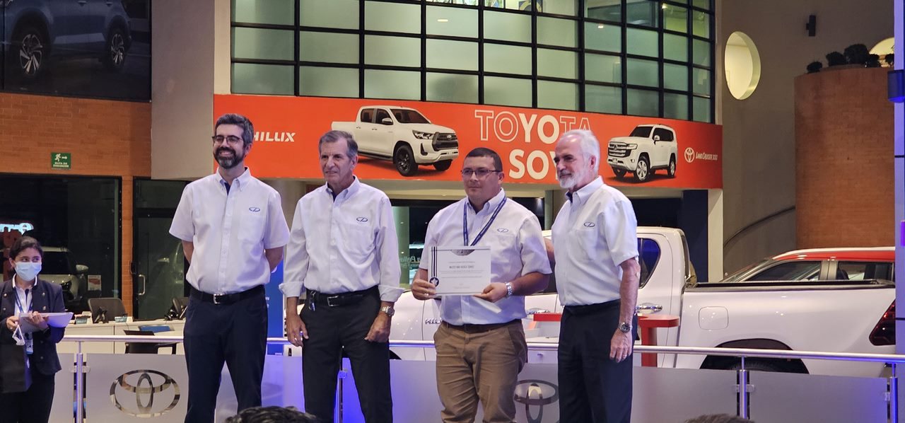 Walter Araica recibiendo un reconocimiento de ventas en el
                      concesionario, junto a tres directivos de la marca.